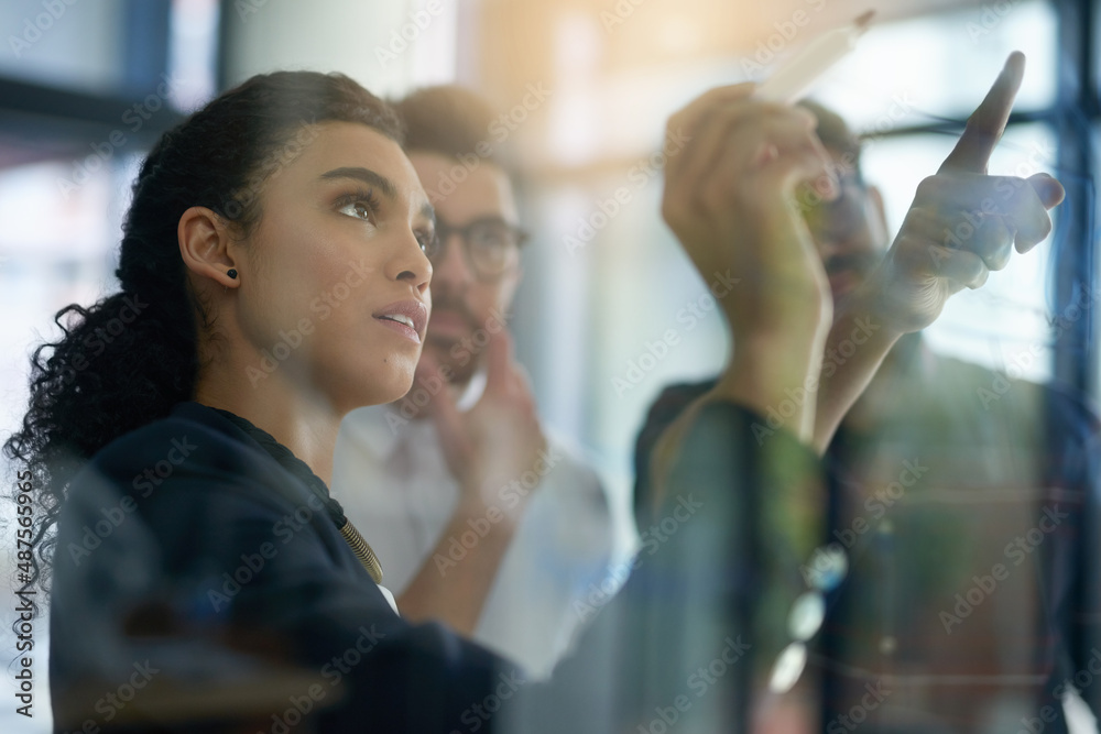 Aufkleber succeeding is top priority. shot of a group of colleagues brainstorming together on a glass wall in 