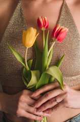 Female hands holding yellow and pink spring flowers tulips. Feminine details of beauty and inspiration