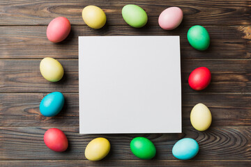 round frame multicolored Easter eggs with white blank paper on a brown background, close-up, space for text, blank for design, selective focus, tinted image