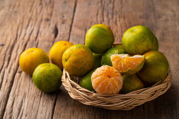 Peeled and unpeeled Thai orange Tangerine on wicker basket on wooden plate background