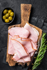 Pork ham slices on cutting board, Italian Prosciutto cotto. Black background. Top view