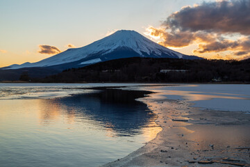 氷結の山中湖から湖面に映る富士山と夕焼け