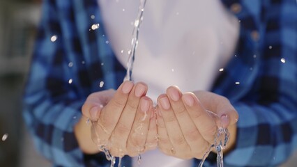 transparent clean water pours on human hands from top to bottom, eco, conservation of renewable resources, a splash of refreshing streams of coolness on the fingers, splashes of wet and wet drops