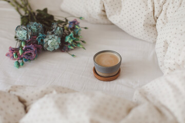 Fototapeta na wymiar Good morning, Flat lay composition with coffee cup, blue flowers and warm blanket in cozy bed, top view