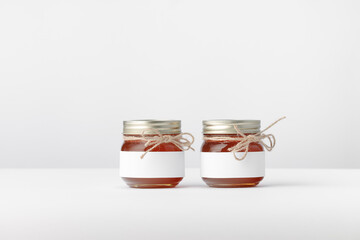 Two Jars with Honey, Twine and white Label on a white background