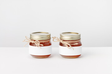 Two Jars with Honey, Twine and white Label on a white background