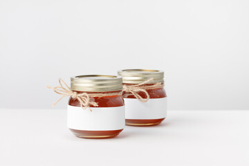 Two Jars with Honey, Twine and white Label on a white background