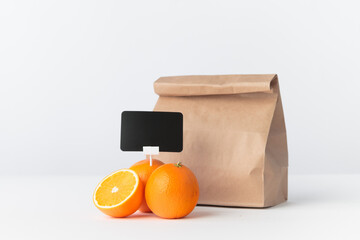 Oranges with a price holder and a paper shopping bag