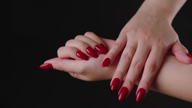 Crop woman with red nail polish. High angle of crop faceless female showing hands with red manicure against black background in studio