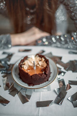 dessert with a birthday candle against a backdrop of glittery tinsel
