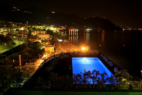 High angle view of the town of Gioiosa marea at night with blue swimming pool