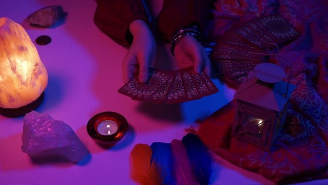 Woman spreading out tarot cards in her hands in a mystical setting. Cyberpunk blue pink neon light. Predicting the future, esoteric, mystic.