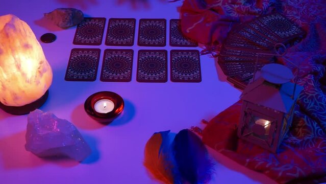Female hands make a mystical movement above the arranged tarot cards. Lined up cards. Cyberpunk blue pink neon light. Predict the future occult, esoteric. 