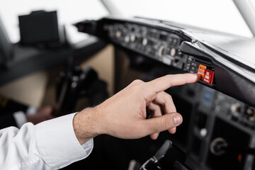 cropped view of pilot pressing master caution button in airplane simulator.