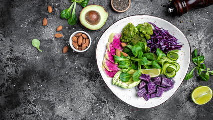 Buddha Bowl with Green vegetable vegan salad with sweet potatoes, broccoli, avocado, purple cabbage, cucumber, watermelon radish and almonds. Clean eating, dieting food concept. top view