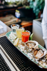Fresh open oysters with a set of shoot alcoholic cocktails served on table. Seafood delicios