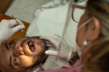 Latin American adult male (42) is examined by a female dentist using a dental mirror. zenithal...