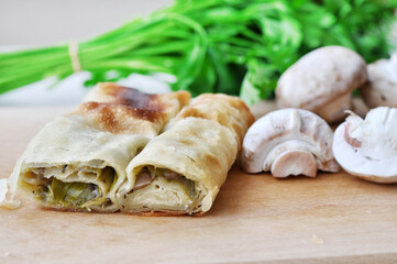 Homemade mushrooms pie.Fresh piece of savory strudel stuffed with  leek and mushrooms served on a wooden plate,with mushrooms and parsley