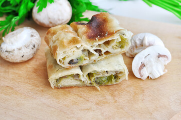 Homemade mushrooms pie.Fresh piece of savory strudel stuffed with  leek and mushrooms served on a wooden plate,with mushrooms and parsley