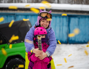Young mother and her daughter having fun in the snow