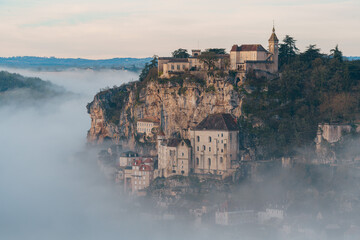 Rocamadour sunrise, Aerial view of the french village and castle on cliff in early morning with fogs in the Canyon of the Alzou - obrazy, fototapety, plakaty