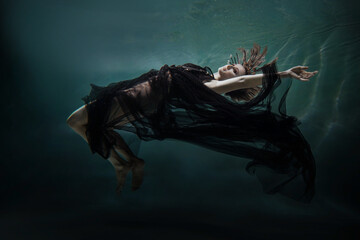 girl sleeping under water. fairy girl in a beautiful dress . underwater photography