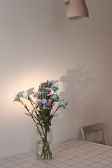 bunch of blue and purple flowers in a jar on the table in a sunny room, minimal home decor