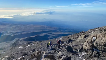 Behang Kilimanjaro A group of tourists climb up the mountain. Climbing Kilimanjaro, Tanzania, Africa
