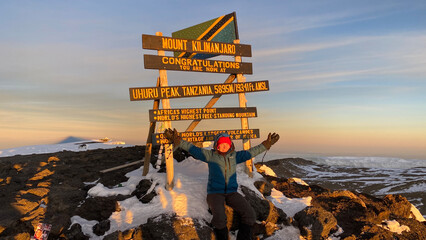 Happy hiker on top of Mount Kilimanjaro. Breathtaking sunrise in the mountains.
