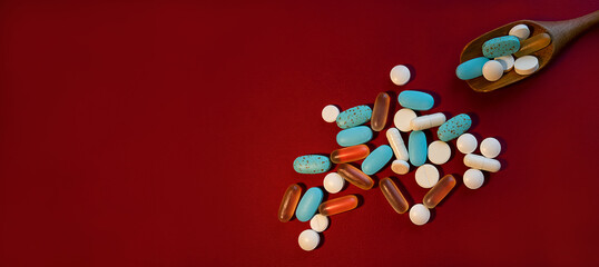 Fototapeta na wymiar Red background with scattered pills and free space, top view. Pills, treatment, health care concept.