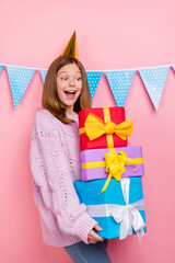 Vertical photo of sweet excited girl knitwear sweater headwear looking presents pile isolated pink color background