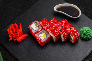 sushi rolls laid out on a dark background decorated with bamboo leaves and chopsticks