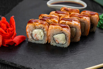 sushi rolls laid out on a dark background decorated with bamboo leaves and chopsticks