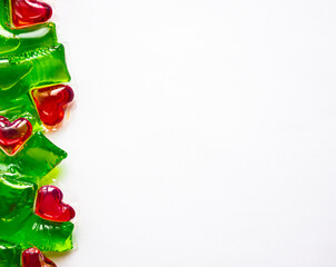 Washing capsules on a white background. Liquid laundry detergent in red-green heart-shaped capsules.