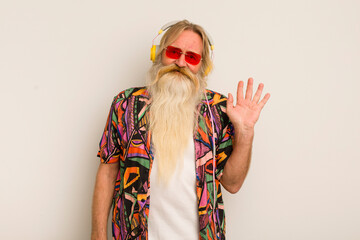 cool senior man smiling happily, waving hand, welcoming and greeting you