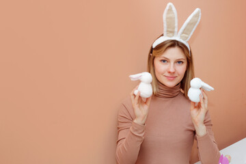 Beautiful young woman with bunny ears on pink background. Making Handmade Easter decoration little rabbit