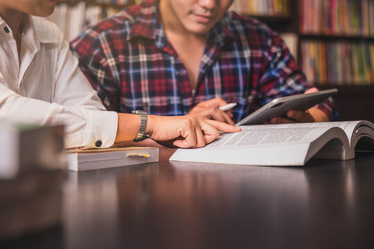 studen sitting pointing, studying and checking, tutoring books with college students friends. Teaching helping and study course, Team of young teacher or tutor helps students to learning in classroom.