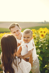 Mother, father and son in white clothes at the sunflowers field