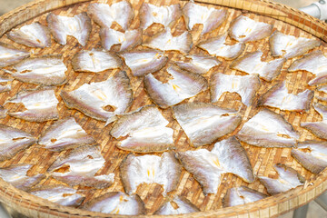 Dried salted fish in the sun on the woven bamboo basket as food preservation.