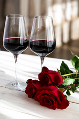 romantic dinner. Two glasses of wine with roses and petals.
