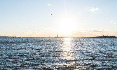 Statue of Liberty in the distance on a cold, sunny day in NYC.