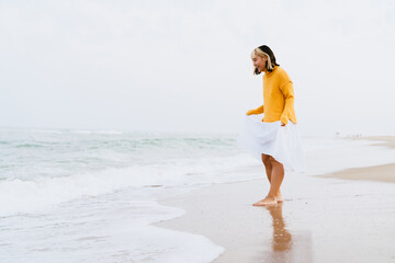 Young woman wearing sweater smiling during walking on beach