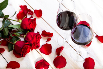 Fototapeta na wymiar romantic dinner. Two glasses of wine with roses and petals.