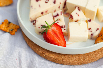 Summer picnic with Wensleydale cheese and cheddar cheese, Strawberries, pears and milk on the cork kitchen stands and grey fabric. Close up half of the strawberry