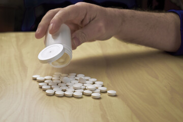 a man pours pills out of a plastic bottle on the table