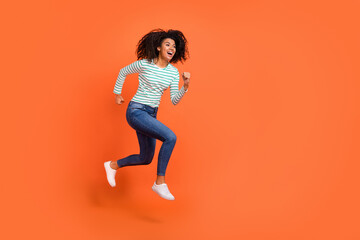 Fototapeta na wymiar Full body photo of young lady run wear shirt jeans sneakers isolated on orange background