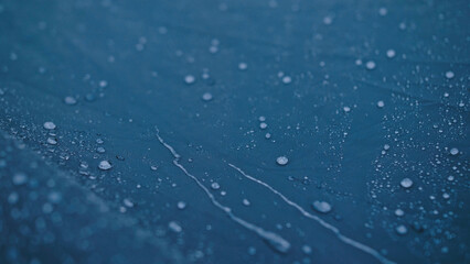 Close-up shot of raindrops water droplets on the tent. Dew drops on texture of fabric of tourist tent in rays of rising or setting sun. Camp, hiking tourism. The rain is pounding on tent.