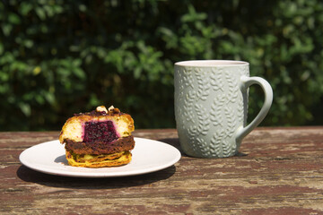 Muffins of small sizes with raspberries on a green background in bright sunlight in the garden. Summer mood.Confectionery blog,banner in a cafe and a restaurant. Menu of confectionery.A tempting offer