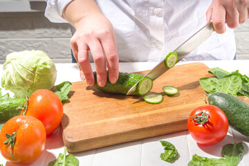 Close-up of cutting slicing fresh cucumbers. Womans hands cut with knife fresh cucumbers vegetables