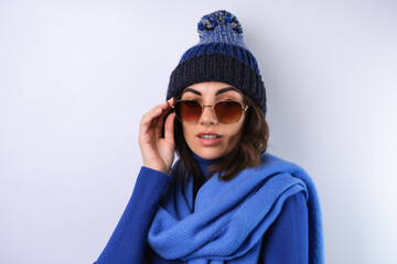 Young woman in a blue golf turtleneck, hat and scarf, sunglasses, on a white background
